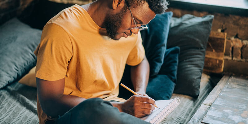 side-hustles-man-writing Freelancer writes down creative ideas in his notebook