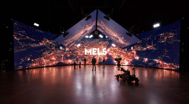 Virtual-production-mels-stage The MELs studio logo displays over top of a cityscape on a virtual production stage