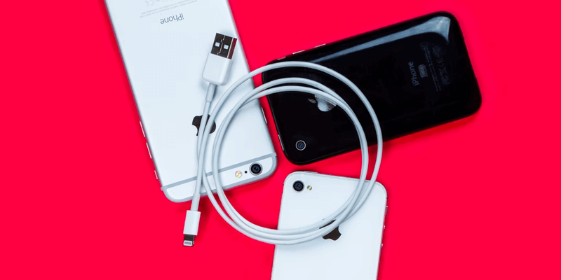 iPhone 13 ProRes-Dateien_Blitzkabel Ein Apple-Lightning-Kabel liegt auf drei iPhones